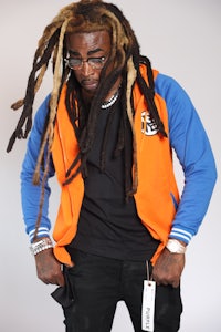 a man with dreadlocks wearing an orange jacket